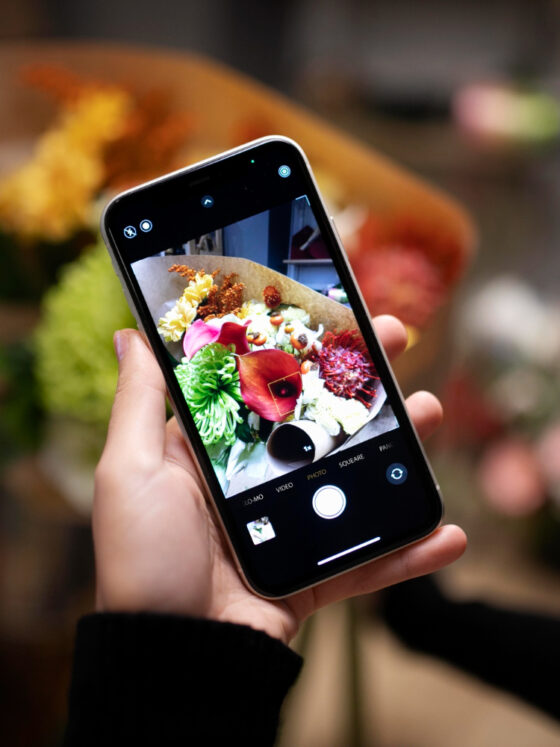 Chica tomando una foto de un ramo de flores